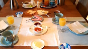 Une table de petit-déjeuner avec une longue table, des assiettes remplies de nourriture et divers condiments.