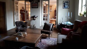 Un salon chaleureux avec une table basse en bois, deux fauteuils, un tapis à motifs et un lustre.