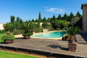 A swimming pool with a wooden deck and potted plants. - Stockowners Farm House (Howick)