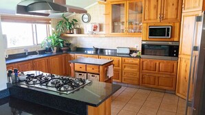 A kitchen with wooden cabinets, a gas stove, a microwave, and a sink. - Stockowners Farm House (Howick)
