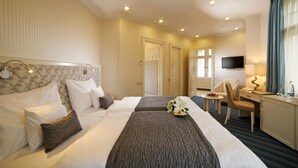 Une chambre d’hôtel avec deux lits, un bureau, une chaise, une télévision et une fenêtre avec des rideaux.