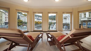 Une pièce dotée de quatre fauteuils inclinables et de grandes fenêtres donnant sur un panorama urbain.