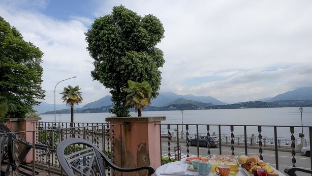 Una mesa con alimentos para el desayuno con vistas a un lago y montañas al fondo.