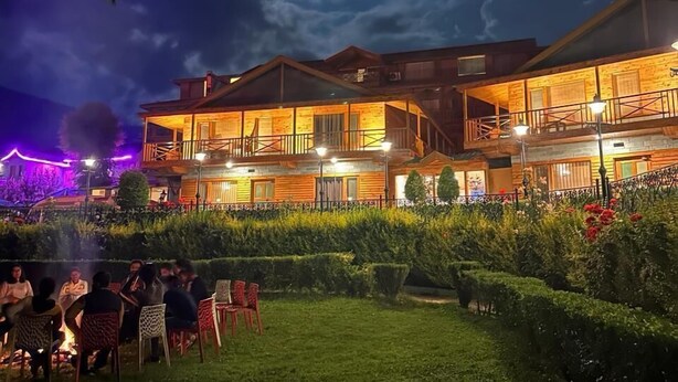 A two-story lodge with a covered outdoor seating area and a well-maintained garden. - Daffodil Cottages (Manali)