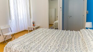 A bedroom with a bed, a chair, a small table, and a door. - B&B Le Marinelle (Salerno)