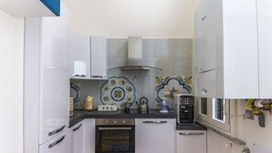 A kitchen with white cabinets, a built-in oven, a coffee maker, and a tea sign. - B&B Le Marinelle (Salerno)