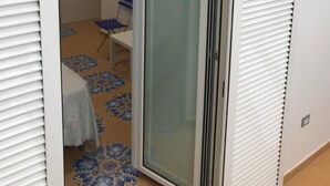 A room with a sliding glass door leading to a small patio area with a table and chairs. - B&B Le Marinelle (Salerno)