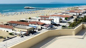 A coastal town with a beach, a pier, and buildings with red roofs. - Hotel Capri & Residence (Camaiore)