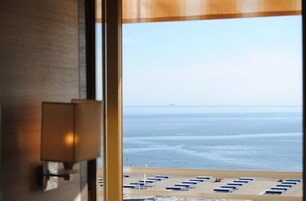 A view of the ocean through a window with a lamp on the left.