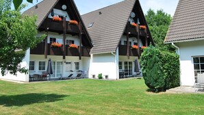 A traditional chalet-style building with multiple balconies, a well-maintained lawn, and outdoor seating.