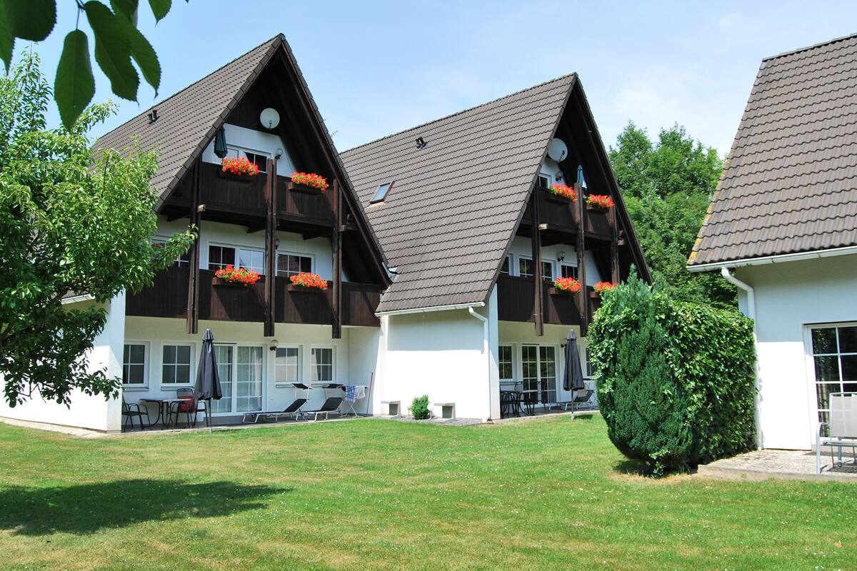Un bâtiment de style chalet traditionnel, doté de nombreux balcons, d’une pelouse bien entretenue et d’un espace salon extérieur.