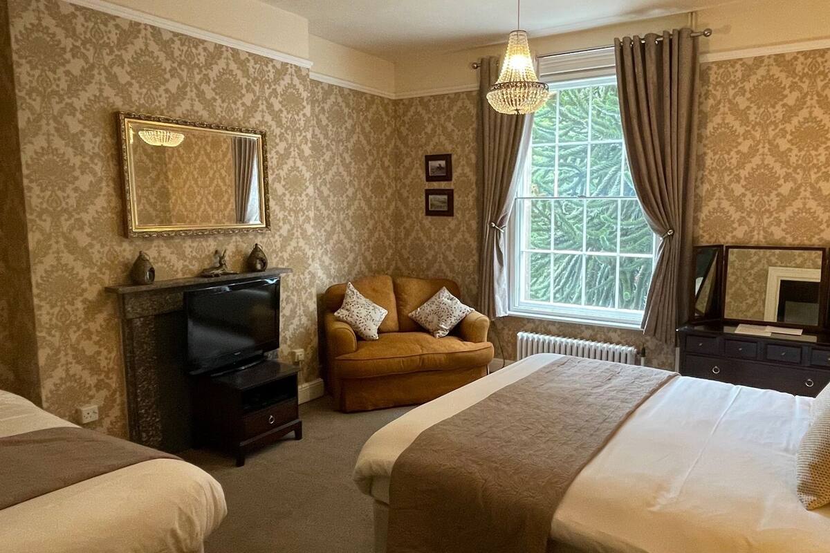 A hotel room with a fireplace, a sofa, a bed, and a large window with curtains.