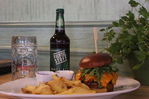 Un piatto con un hamburger, patatine fritte e una bottiglia di birra.