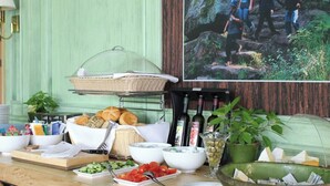 A buffet setup with various food items, a wicker basket, and a bottle of olive oil. - Spa & Wellnesshotel Bad Alexandersbad (Bad Alexandersbad)