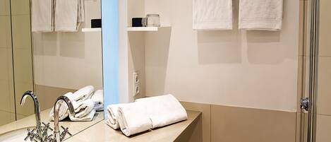 A modern bathroom with a sink, mirror, and two towels hanging on a towel rack.