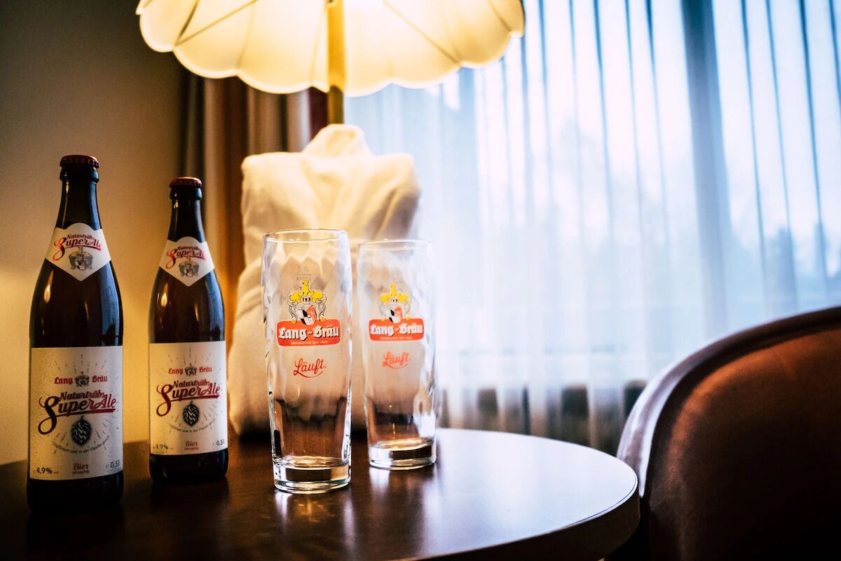 Deux bouteilles de bière, deux verres et une lampe sur une table.