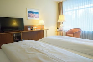A hotel room with a bed, a television, a desk with a lamp, a chair, and a window with curtains. - Spa & Wellnesshotel Bad Alexandersbad – Fichtelgebirge by Belvilla (Bad Alexandersbad)