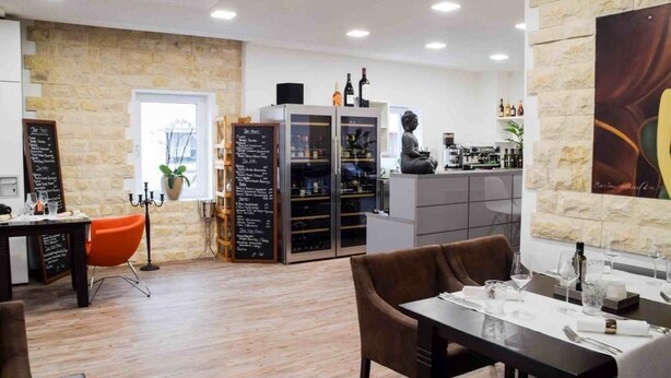Un interior de restaurante moderno con paredes de piedra, una zona de bar y un área de asientos.