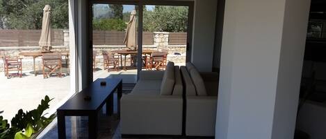 A modern living room with a large glass door leading to an outdoor patio area.