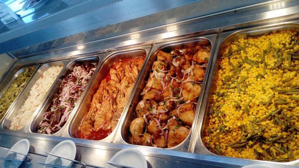 A buffet with various dishes including rice, coleslaw, chicken, and a corn and bean dish.