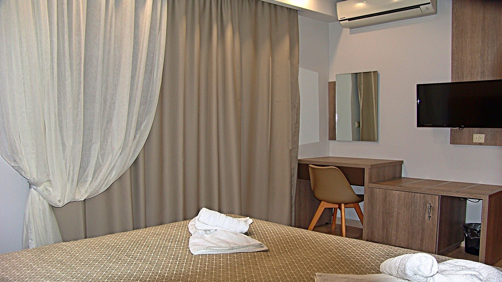 Una camera d'albergo con un letto, una scrivania, una sedia, una televisione e uno specchio.
