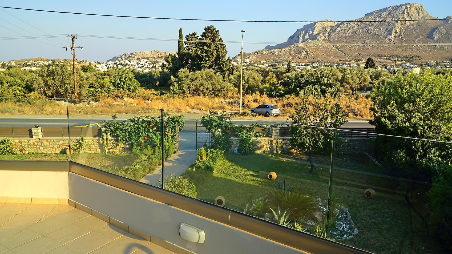 Ein Balkon mit Blick auf eine Straße, Grünflächen und entfernte Gebäude.