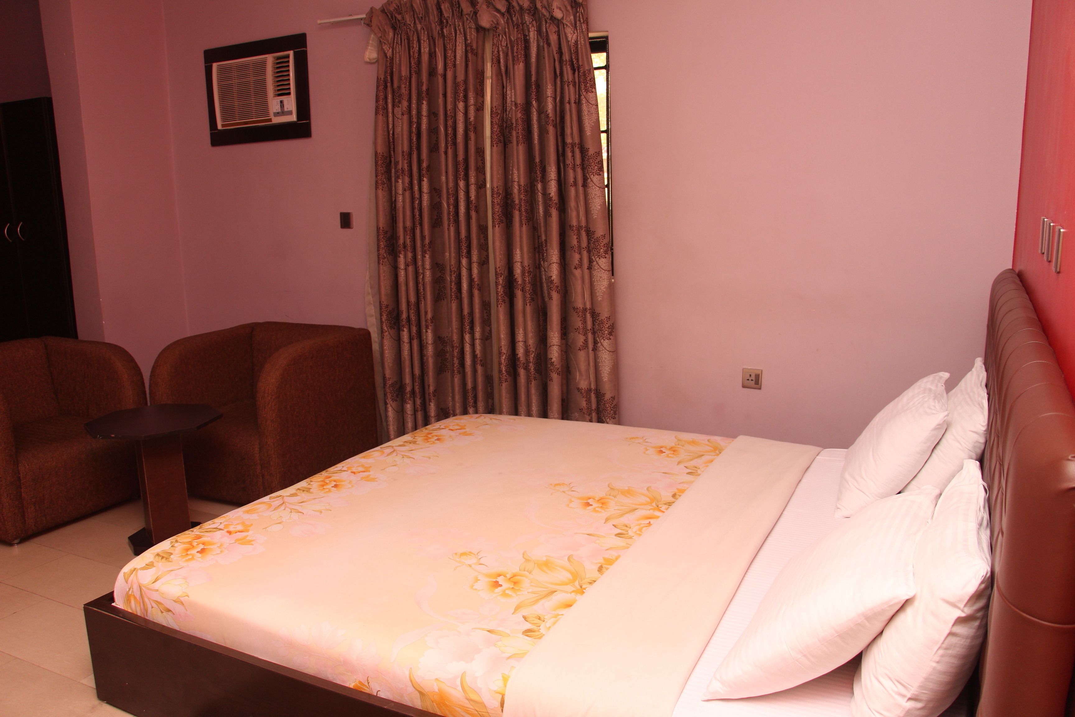 A bedroom with a bed, a chair, a small table, and a curtain.