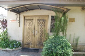 Puerta doble de madera con diseños intrincados, un letrero que indica restaurante y bar, y un acceso cubierto con techo de metal.
