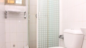 Une salle de bain équipée de toilettes, d’une douche à parois de verre et d’un porte-serviettes.