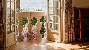 Una puerta abierta con vistas al mar, un banco de madera y una pequeña mesa.