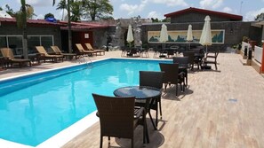 Una piscina al aire libre, sombrillas, sillones reclinables de piscina