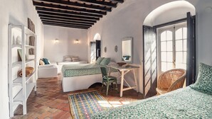 Un dormitorio acogedor con cama, escritorio y silla. Hay una estantería y una ventana con vistas.
