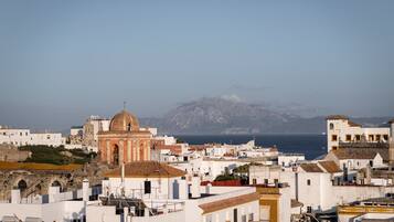 Un poble costaner amb edificis blancs, una església destacada amb cúpula, i una muntanya al fons.