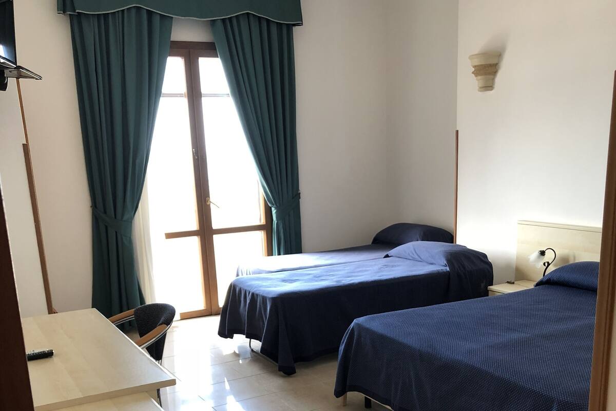 A hotel room with two beds, a desk, and a chair.
