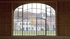 Una ventana con diseño de cuadrícula, paredes de madera y vista a un edificio con tejado de tejas.