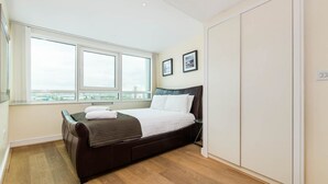 Een moderne slaapkamer met een groot bed, een raam met uitzicht over de stad en een kledingkast.