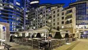Een moderne hotelbinnenplaats met buiten zitplaatsen en uitzicht op wolkenkrabbers.