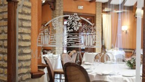 Interior de restaurante con pared de ladrillo, vigas de madera y una mesa blanca lista para comer.
