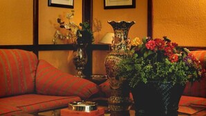Una habitación tradicional con un sofá de madera, una mesa de centro con un libro y un florero con flores.