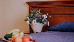 Una cama con un cojín azul y una cesta tejida con flores sobre un cabecero de madera.
