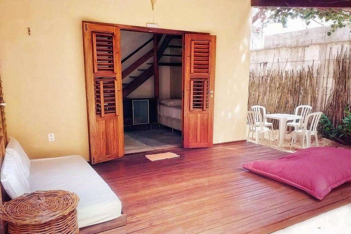 Eine Holzterrasse mit einem Bett, einem Korbwäscher und einem Tisch mit Stühlen.