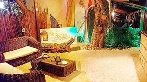 A cozy lounge area with wicker furniture, a signboard, and a rustic wooden wall. - Sunset Jeri Flat (Jijoca de Jericoacoara)