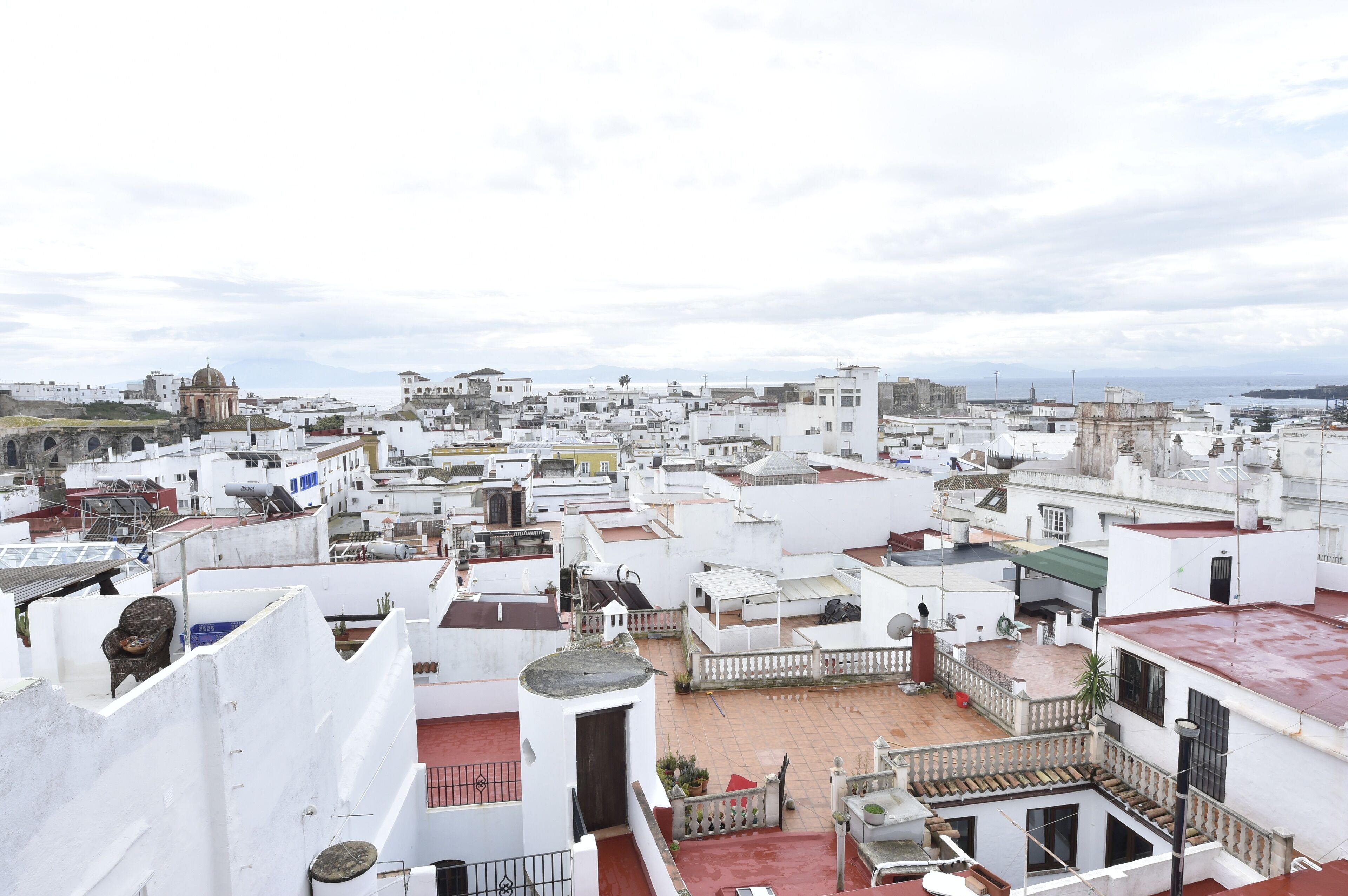 A cityscape with white buildings, a prominent dome structure, and a view of the sea.