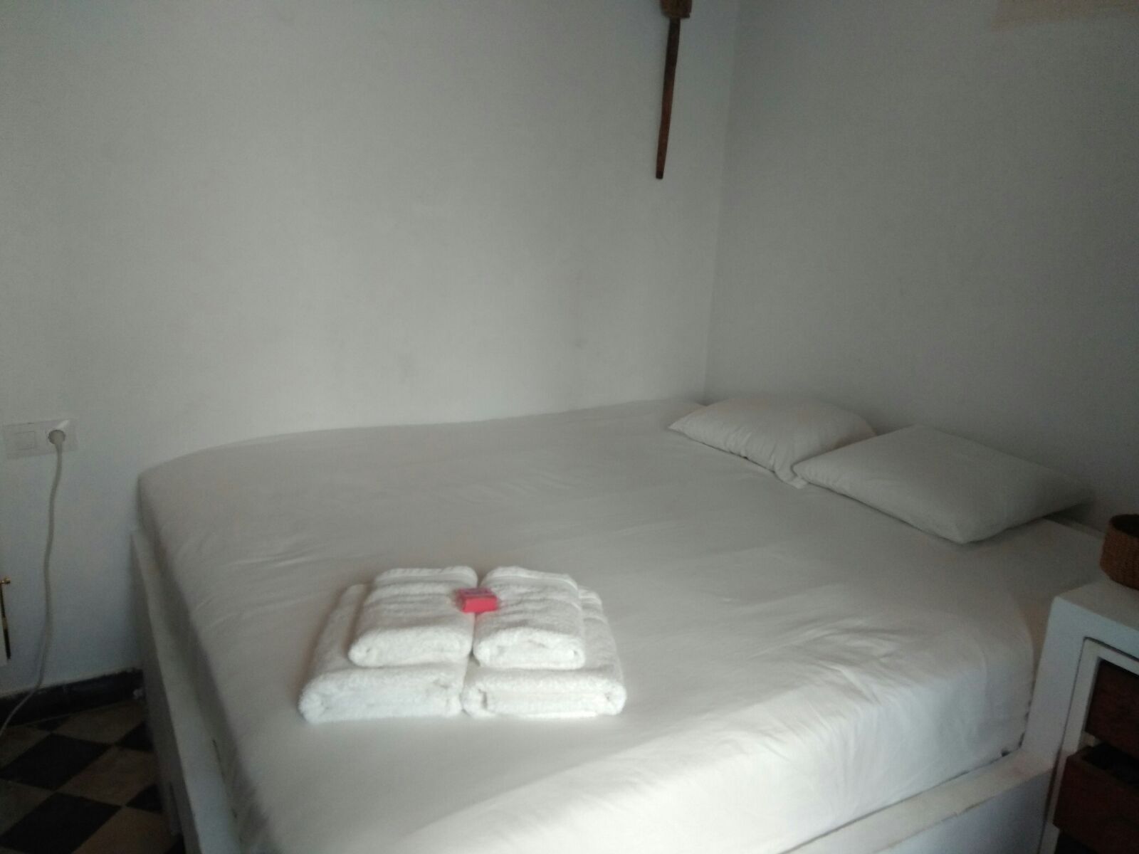 Una cama bien hecha con sábanas blancas y un juego de toallas dispuestas sobre ella.