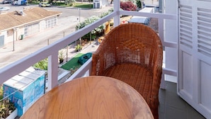 A balcony with wicker furniture, a view of the sea, and buildings in the background. - Hostal Residencia San Francisco (Felanitx)