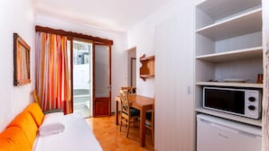A hotel room with a bed, a dining table with chairs, a microwave, and a small refrigerator. - Hostal Residencia San Francisco (Felanitx)