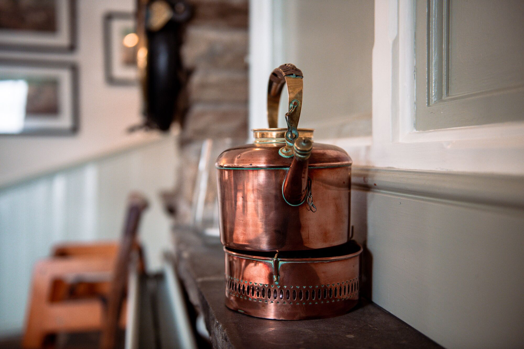 A copper kettle on a wooden shelf.