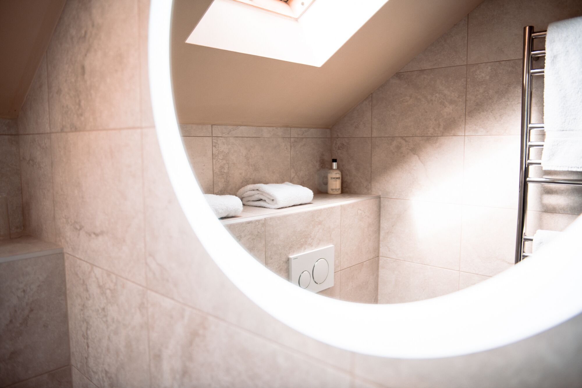 Una ventana circular en un baño con un perchero y una botella de champú.