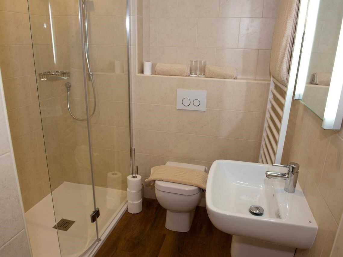 A bathroom with a glass-enclosed shower, a toilet, a sink, and a towel rack.