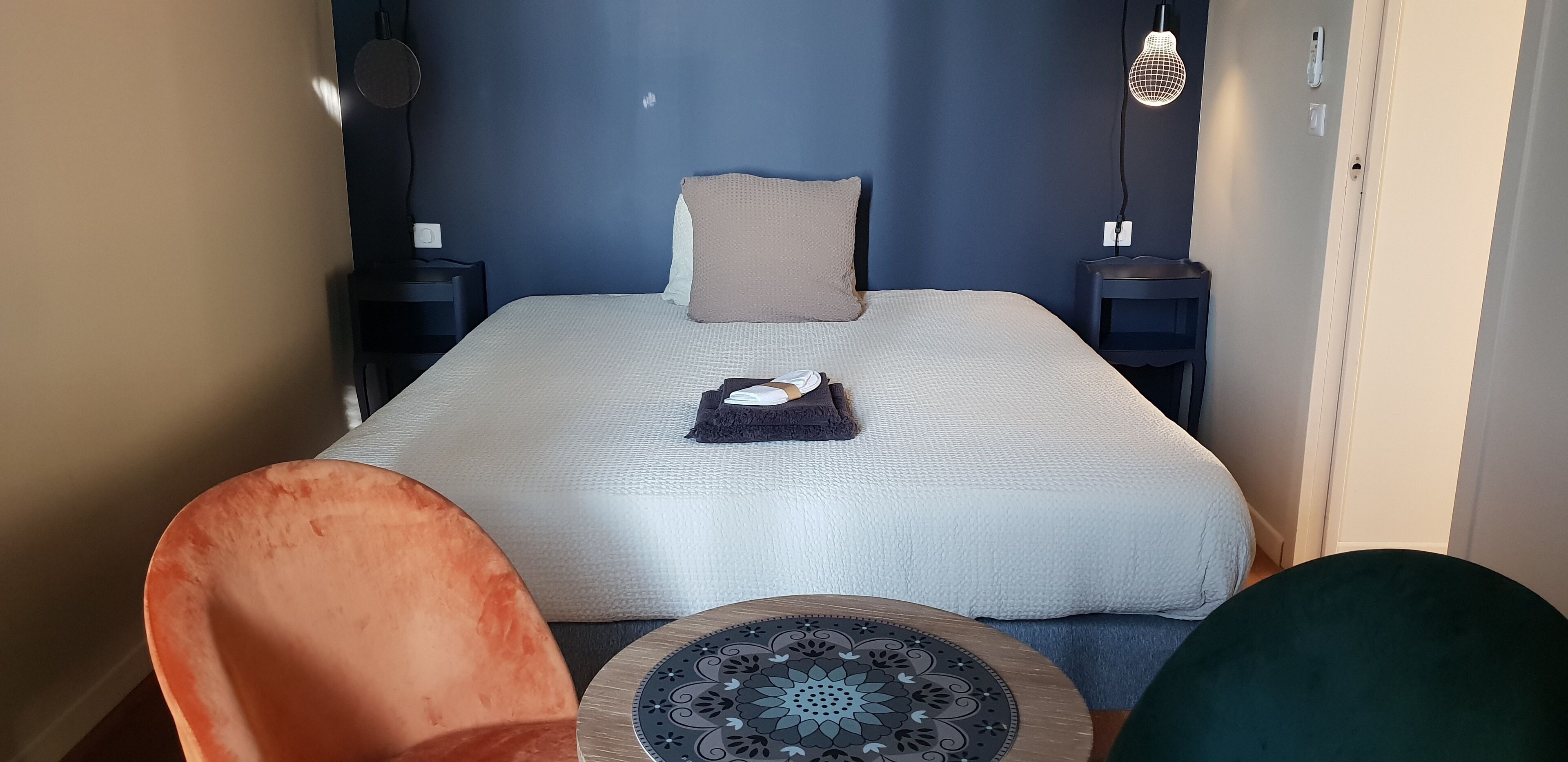 A bedroom with a bed, a bedside table, a chair, and a small table with a decorative item.